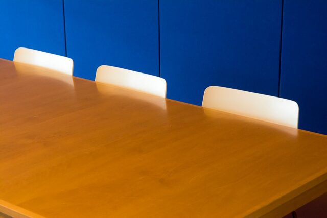 Diverse houten vergadertafels in een moderne vergaderruimte met stoelen